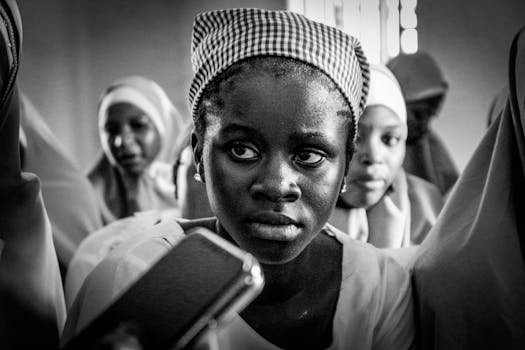 Black and white portrait of Nigerian girls wearing traditional headscarves in a cultural setting.